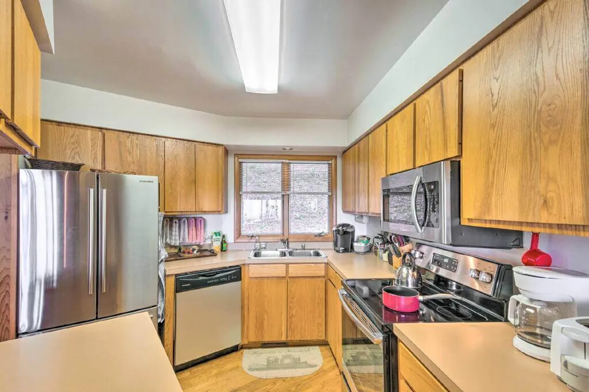 This image features a welcoming kitchen interior with a spacious counter, stainless steel appliances, and a window that lets in ample natural light. The arrangement suggests a practical and inviting space for cooking and gathering with family or friends.