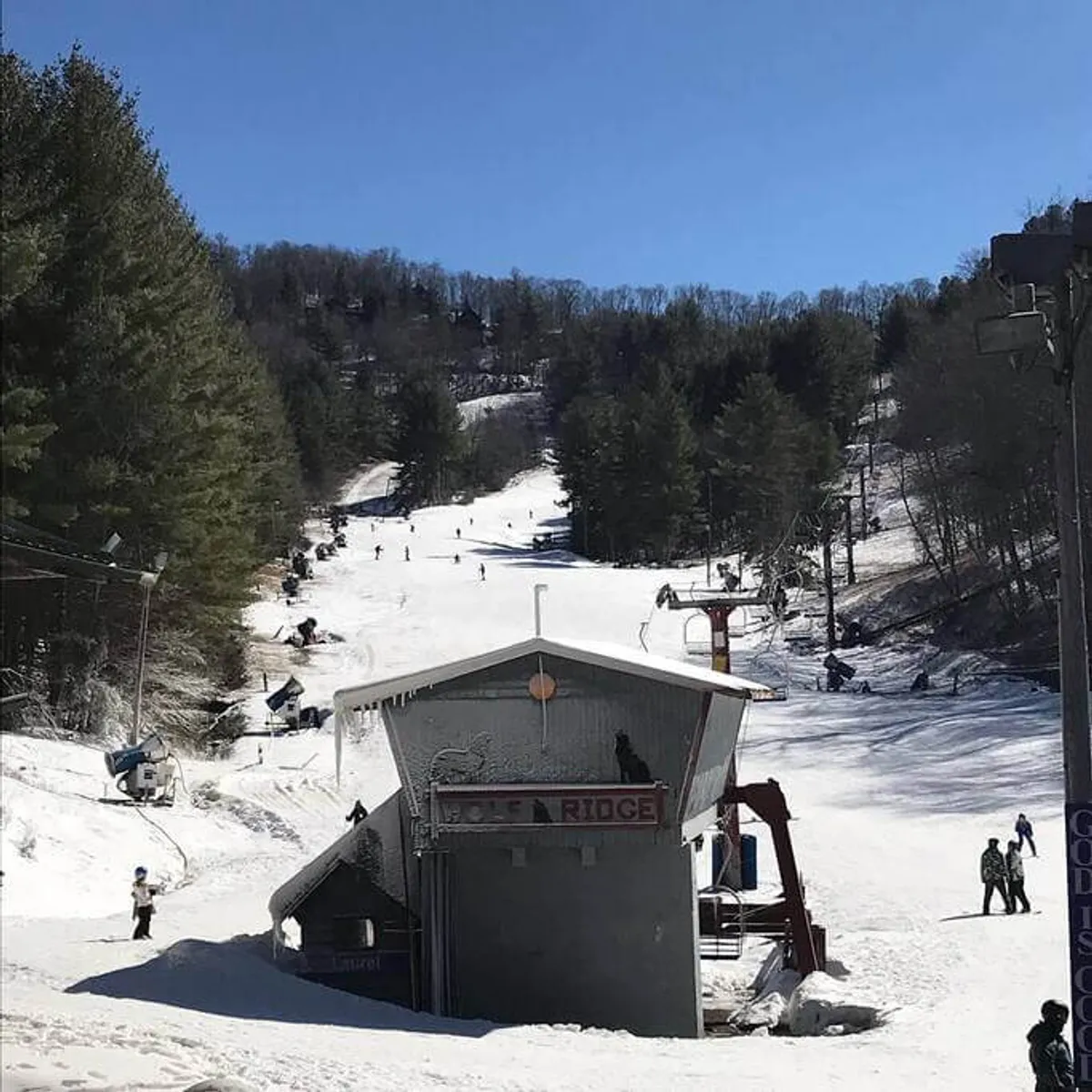 A lively winter scene with a ski lift, snow-covered slopes dotted with skiers and snowboarders, and a cozy lodge building nearby. Families and groups are visible, enjoying the excitement of winter sports and the vibrant atmosphere of the ski resort.