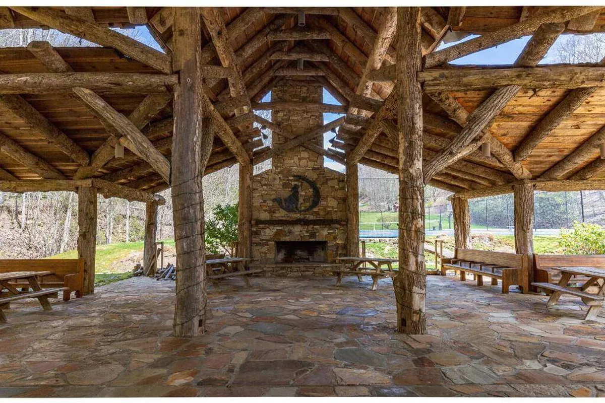 An inviting interior space with a striking stone fireplace, exposed wooden beams, and open benches—ideal for socializing, relaxing by the fire, or enjoying shared meals in a warm and communal ambiance.